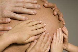 Vue sur des mains posées sur le ventre d'une femme enceinte