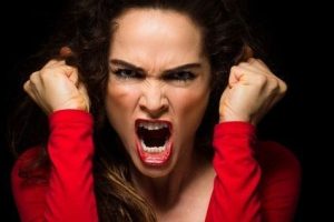 A very angry aggressive woman is clenching her fists in rage