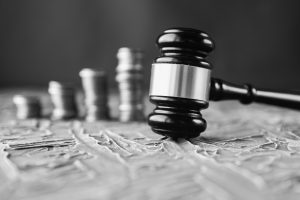 Judge's Hand Holding Gavel Over Stacked Golden Coins