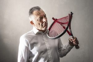 a discouraged man watching his broken tennis racket